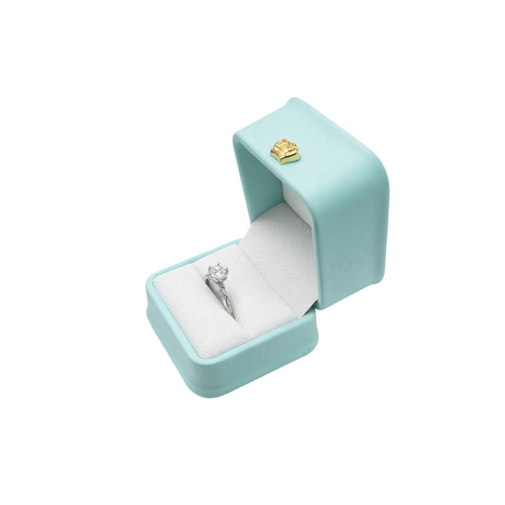 Open mint green rounded-edge ring box displaying a silver-tone ring in the light cushioned insert.