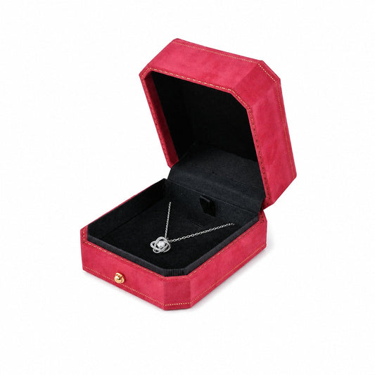 One open red octagonal velvet pendant box displaying jewelry