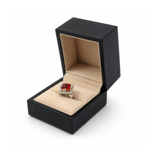 Black ring box with beige lining, open with a red gemstone ring.