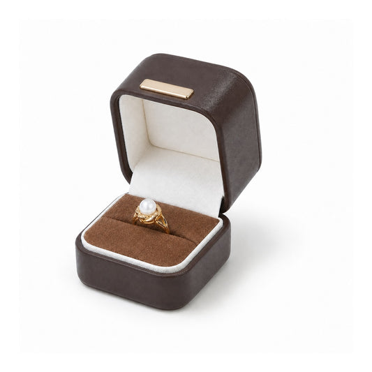 Brown ring box with white piping, open with a pearl ring.
